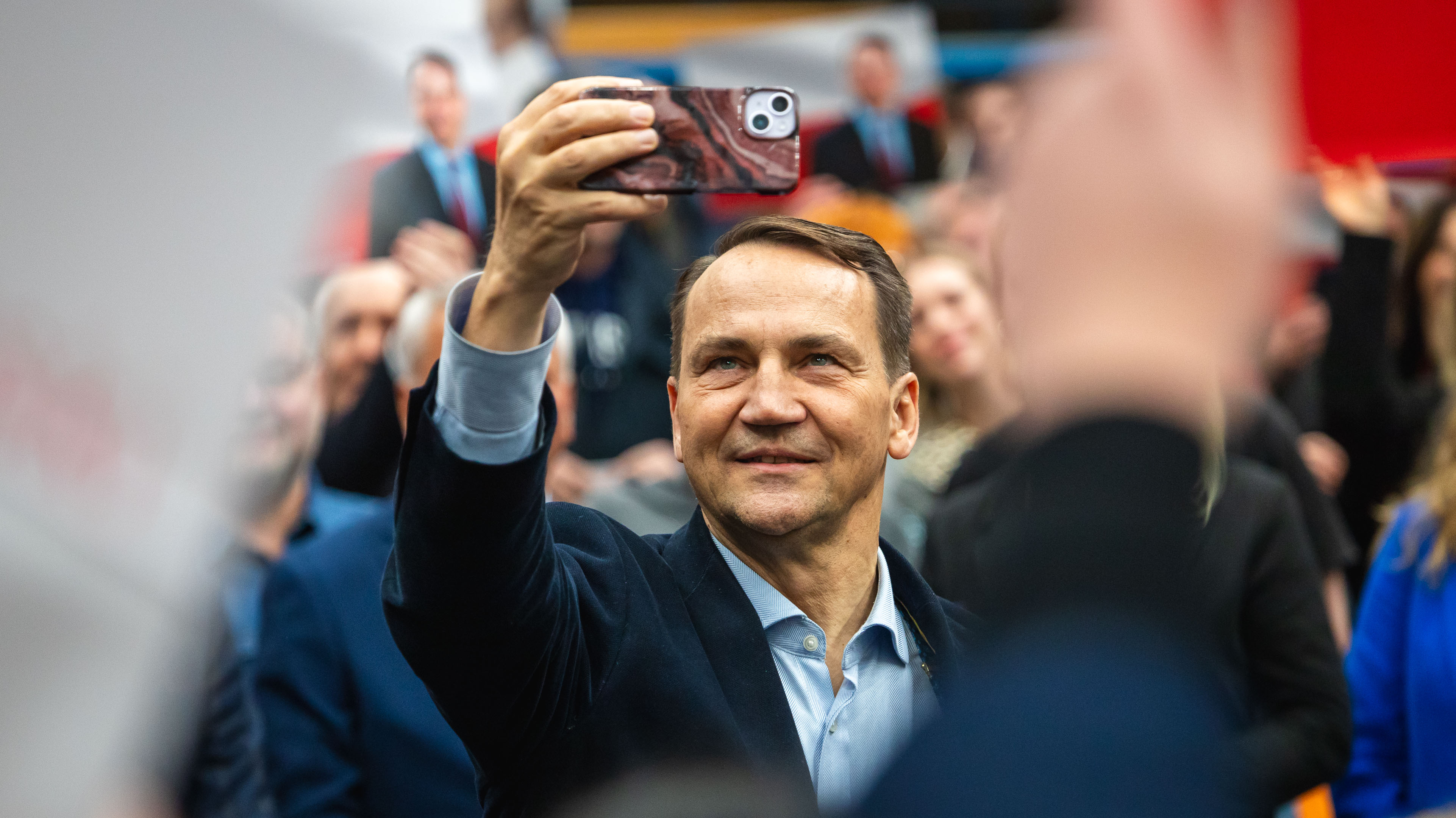 Zdjęcie przedstawia mężczyznę. który trzyma telefon i wykonuje selfie